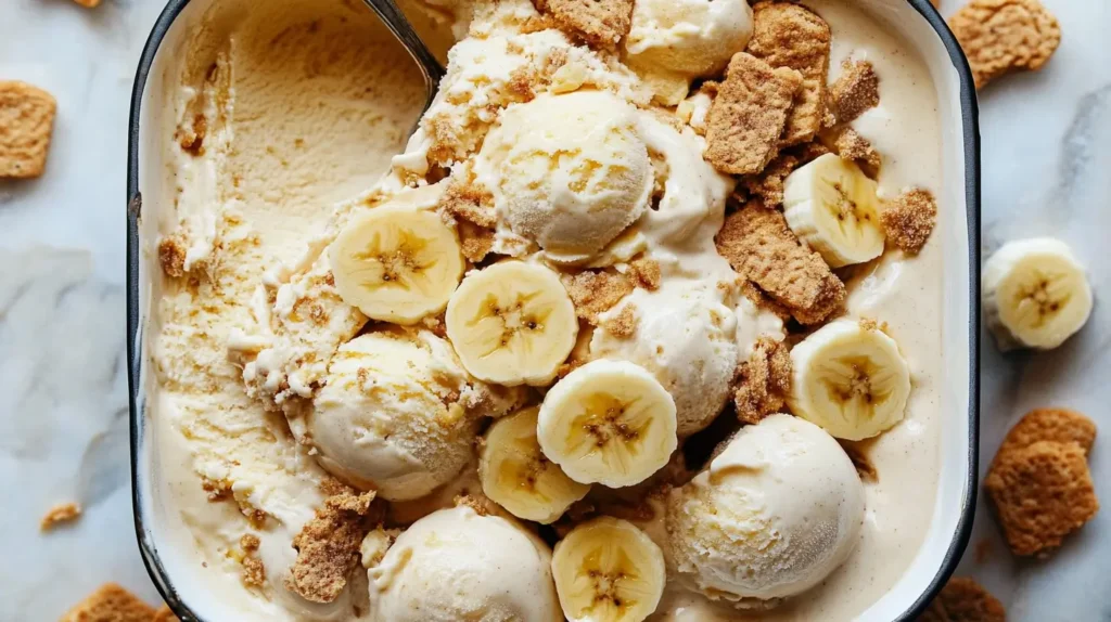 A close-up of creamy banana pudding ice cream with swirls of golden vanilla wafers and fresh banana slices in a rustic bowl.