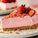 Delicious Strawberry Crunch Cheesecake Recipe 9 A slice of strawberry crunch cheesecake on a white plate, topped with fresh strawberries and crunchy strawberry crumble.