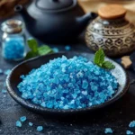 Unlock the Blue Salt Trick: A Natural Stamina Secret for Men 3 Close-up of bright blue salt crystals in a black dish with a glass vial and teapot in background